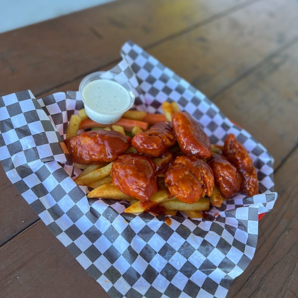 Legends Grill's buffalo wings and fries in a checkered paper-lined basket with a side of ranch.