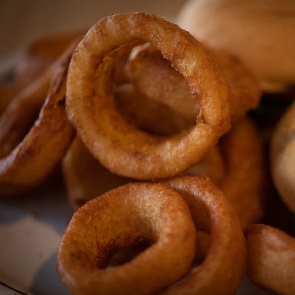 Close-up of golden-brown, crispy onion rings, a classic sports bar appetizer from Legends Grill.